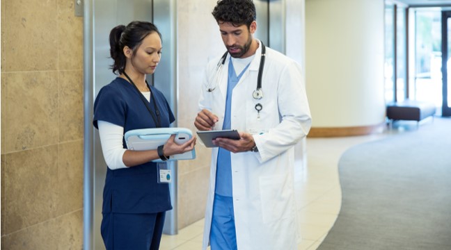 A Doctor and a nurse looking at QC Health on a Microsoft Surface